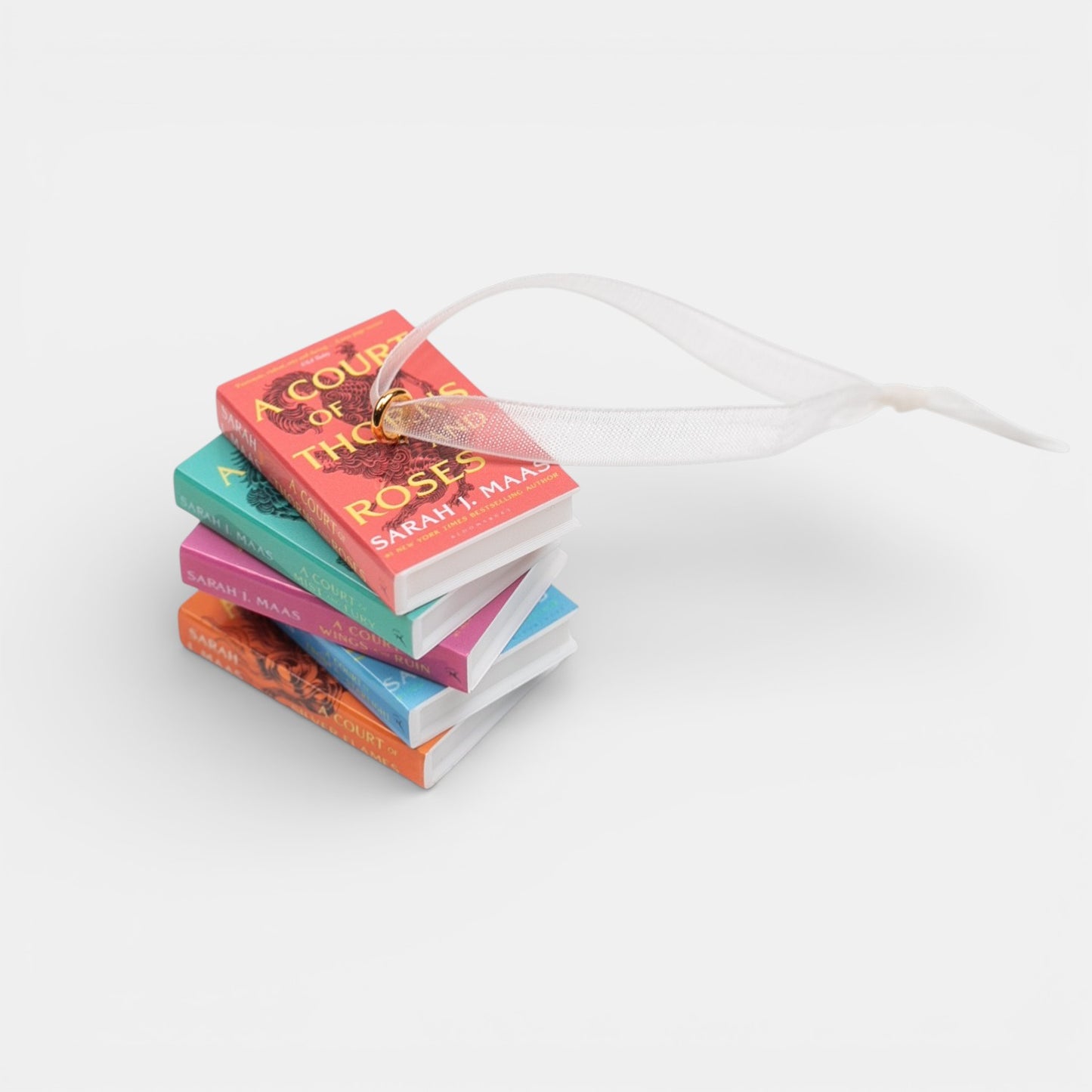 Ornament featuring mini stack of books by Sarah J. Maas on a white background