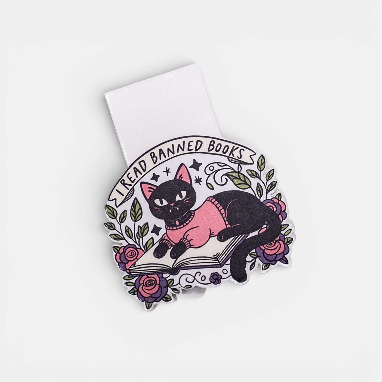 Bookmark of a black cat in a pink sweater on a book with floral elements on a white background.