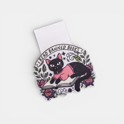 Bookmark of a black cat in a pink sweater on a book with floral elements on a white background.
