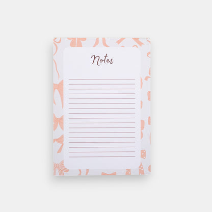 Notepad with pink bow pattern and 'Notes' text on a white background