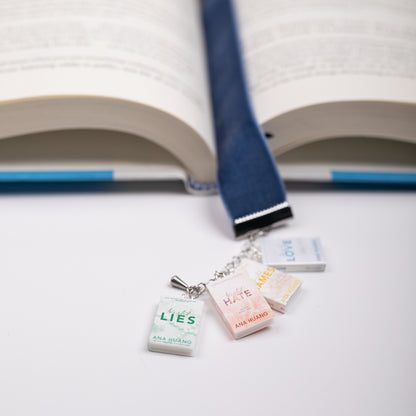 Blue, velvet ribbon with mini book charms of Ana Huang's Twisted series mark the page in an open book