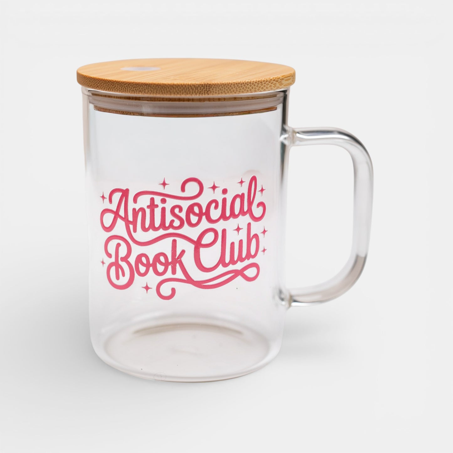 Clear glass mug with bamboo lid and 'Antisocial Book Club' text in pink on a white background