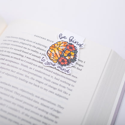 Open book with a decorative bookmark featuring brain and flowers design and text on a white background