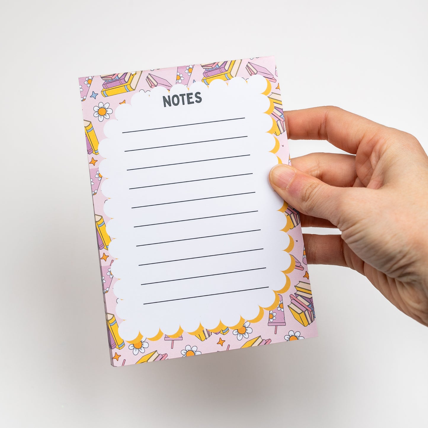 Hand holding a notepad with a colorful border and 'Notes' text on a white background