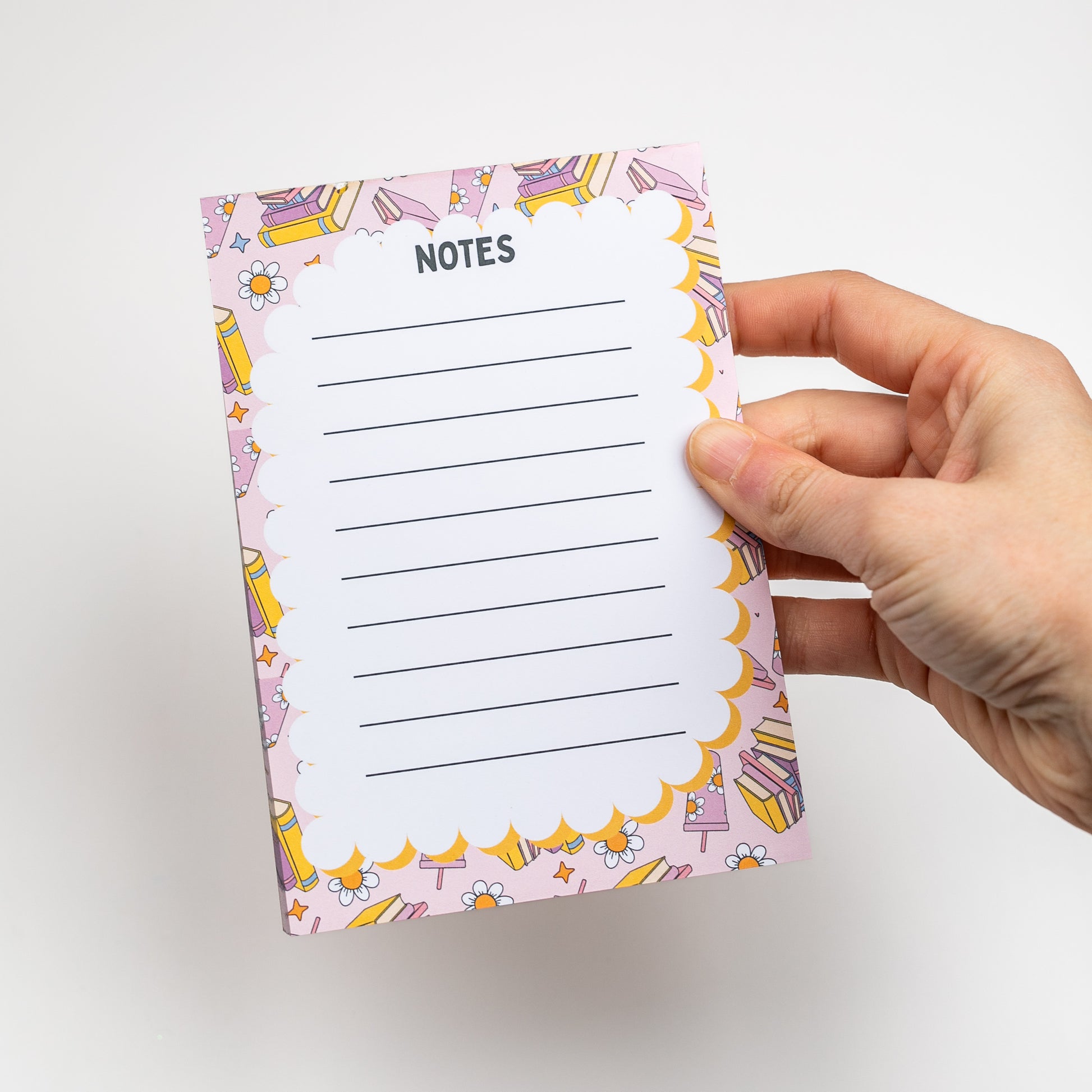 Hand holding a notepad with a colorful border and 'Notes' text on a white background