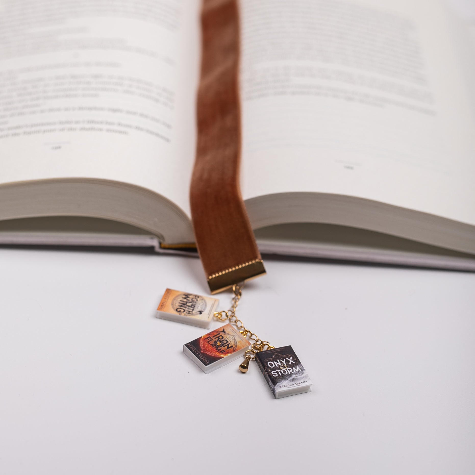 Velvet bookmark with mini Fourth Wing book charms marking the place of an open book