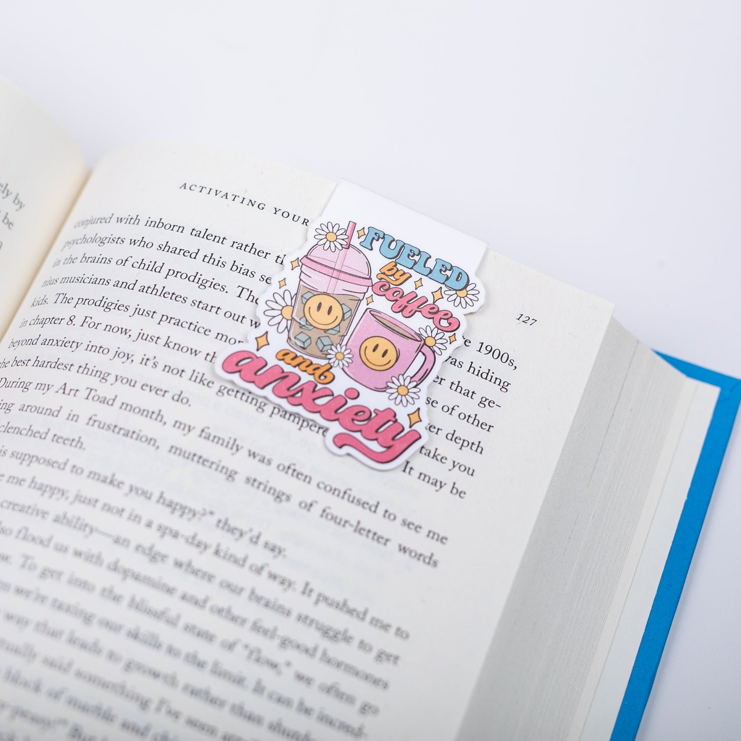 Open book with a bookmark featuring a coffee cups with smiley faces and text on a white background
