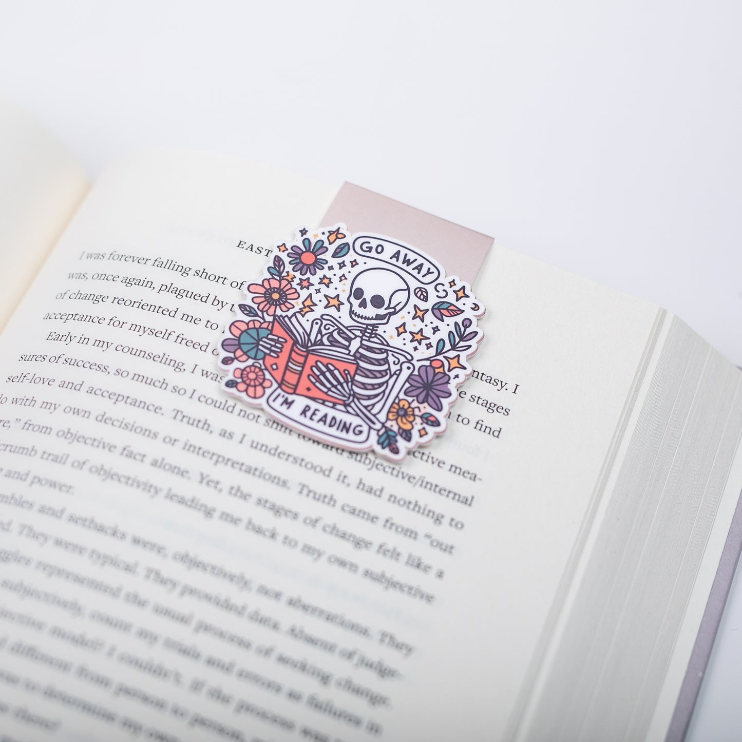 Decorative bookmark with skeleton and floral design on an open book