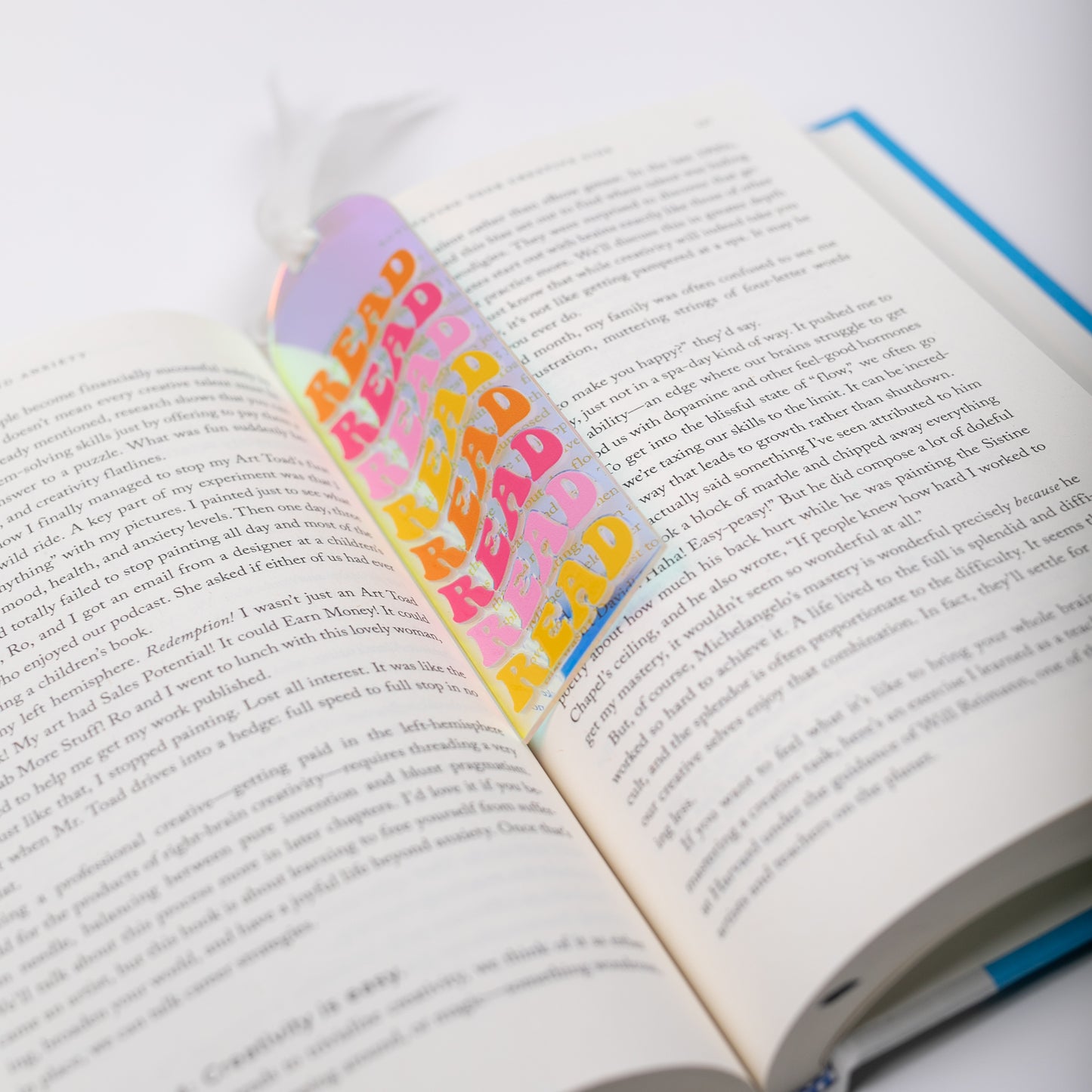 Open book with colorful, holographic bookmark featuring the word 'READ' on a white background