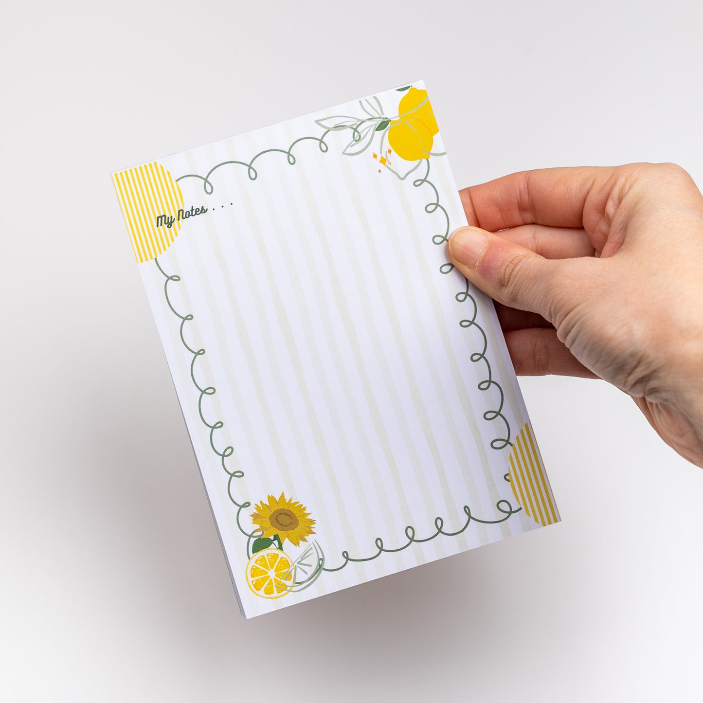 Hand holding a notepad with floral designs on a white background