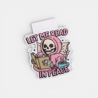 Magnetic bookmark with a skeleton in a pink hoodie reading a book, with text 'Let me read in peace' on a white background.
