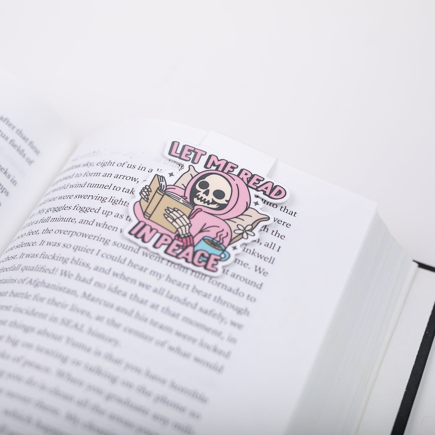 Bookmark with a skeleton reading a book on an open book
