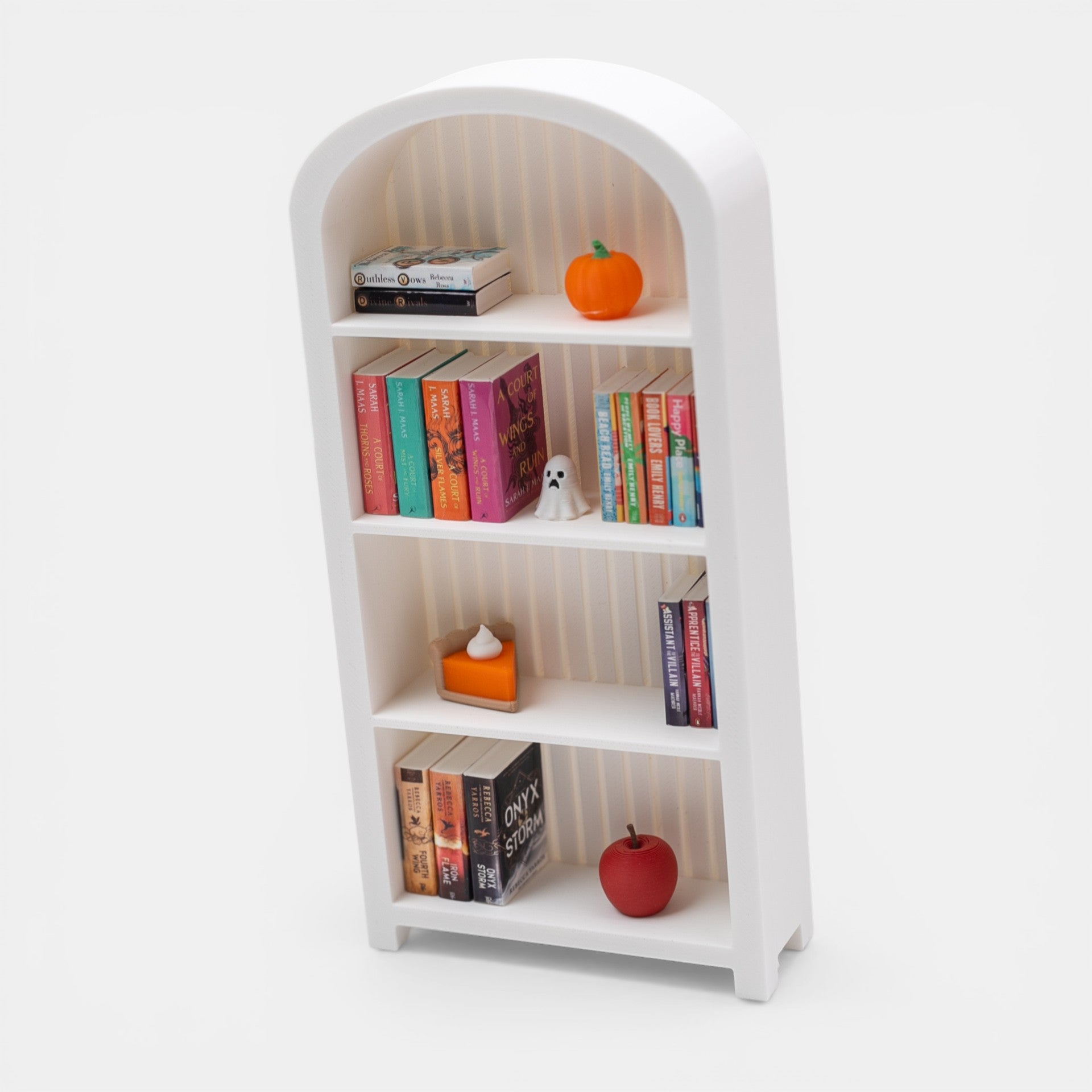 Miniature white bookshelf with books and decorative items on a white background