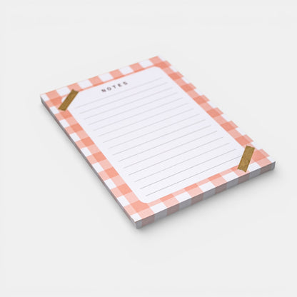 Notepad with a pink and white checkered border on a light gray background