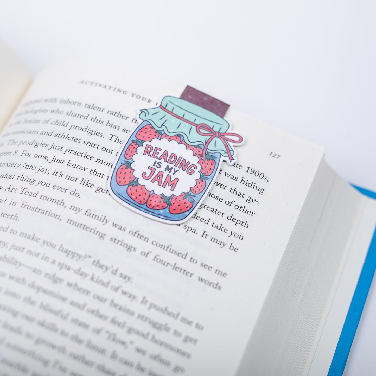 Bookmark with a colorful illustration of a jar labeled 'Reading is my Jam' on an open page.
