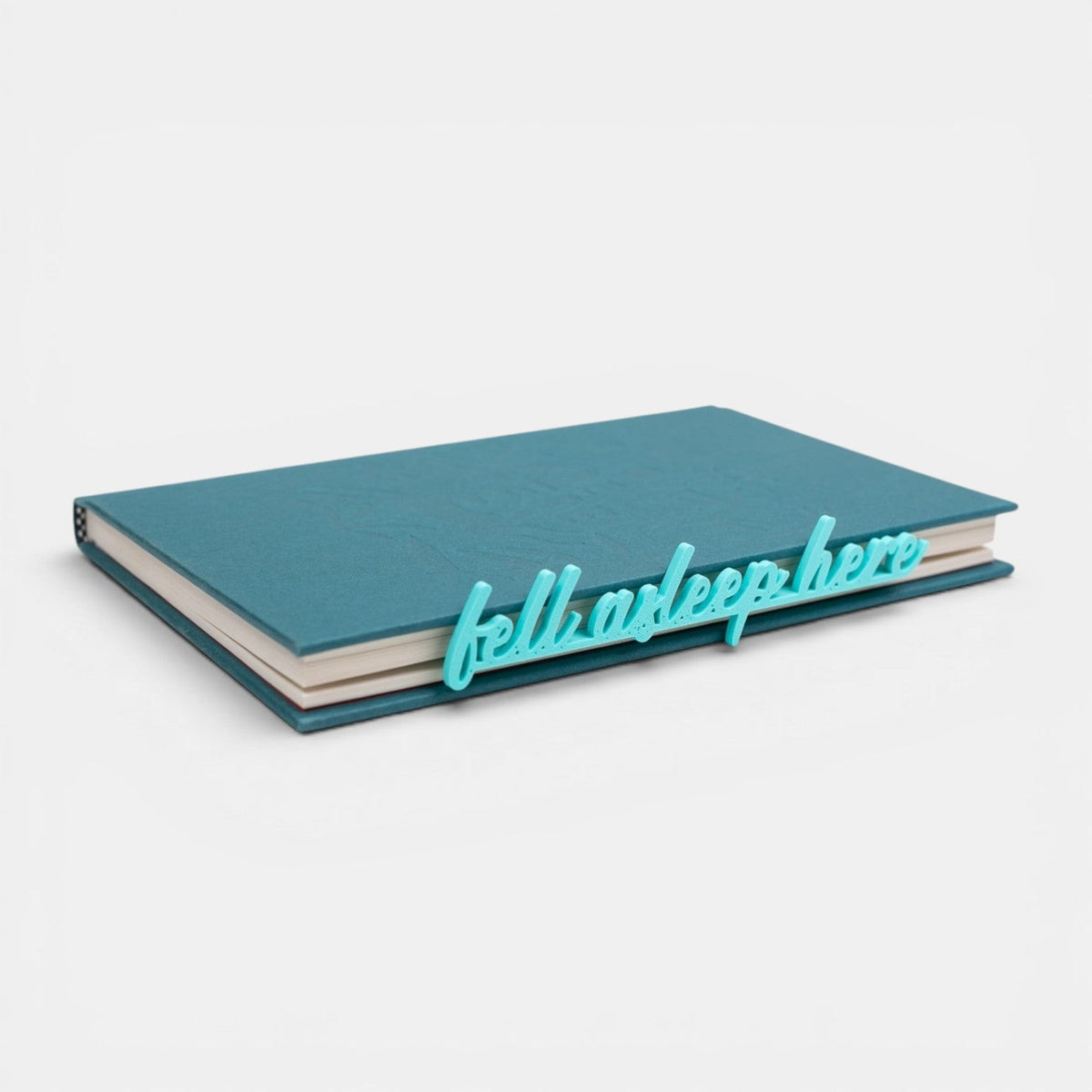 The Salty Cat Co Fell Asleep Here bookmark in teal, featuring cursive lettering resting on a closed teal book.
